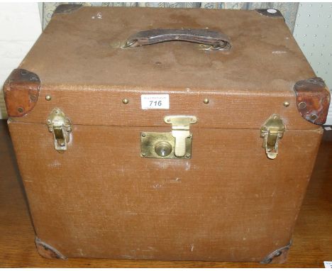A stylish leather bound canvas trunk of square proportions.