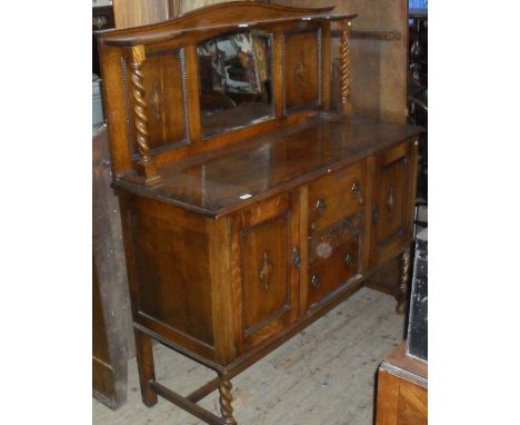 A 1920's/30's oak sideboard, having mirror back with barleytwist columns, having two drawers flanked by two panelled cupboard