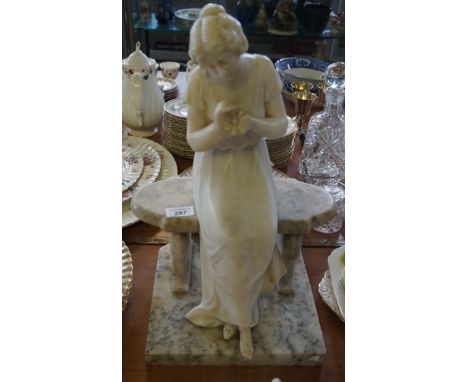 A late 19th/early 20th Century marble figure, depicting a spurned lady seated on a bench holding a daisy, height 46cm (af).