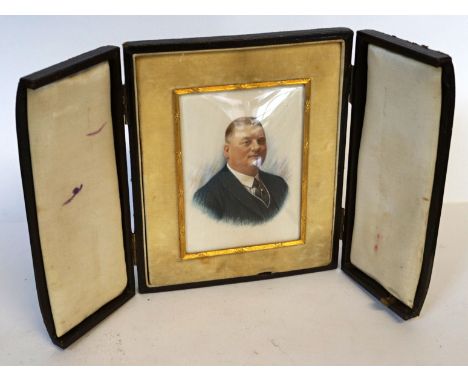 A hand painted portrait miniature of a gentleman wearing a green blazer inset in a leather travel case.