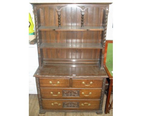 A 1920s/30s oak dresser with plate rack back, having two fixed shelves, raised on two short above two long drawers, terminati