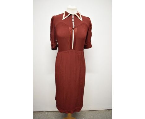An Art Deco day dress of burgundy crepe, having collar with contrasting edge, buttons to bodice, smocking to sleeves and bodi