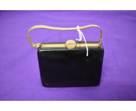 A 1950s bag/compact, having various compartments to hold a comb, writing paper, face powder and cigarettes etc.