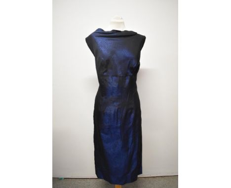 A 1950s gown of metallic blue fabric, having high slash neckline and low back with bow and sash detail, side metal zip and Ma