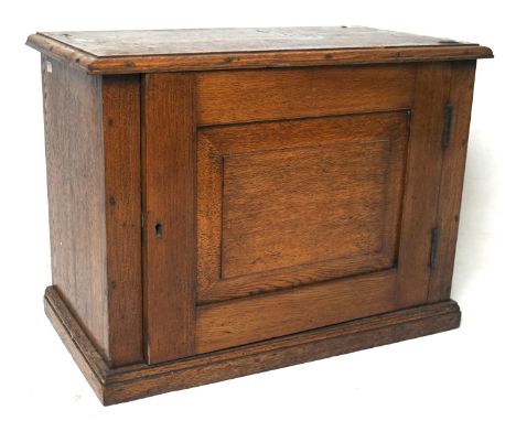 A 20th century small oak cabinet, of rectangular form with a bevelled panel to the door, containing a single shelf, key prese