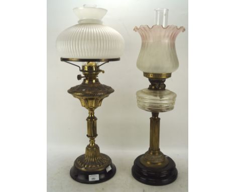 Two late 19th and early 20th century oil lamps, with glass, ceramic and brass reserves, both with glass shades, height of tal