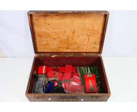 Meccano - A wooden chest with Meccano parts and pieces including wheels, pulleys and a clockwork motor and more and also cont
