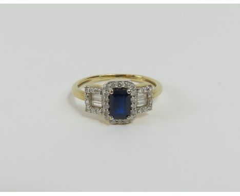 A 9ct gold sapphire and diamond cluster ring, the step cut sapphire with a row of small diamonds surrounding it and with furt