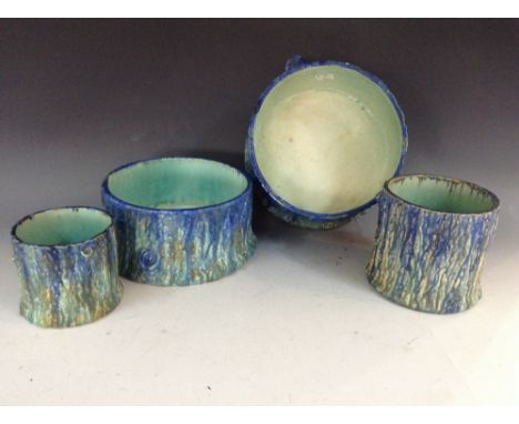 A graduating pair of Bretby tree trunk-shaped circular planters, glazed in mottles tones of blue, green and yellow, the large