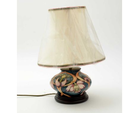 A Moorcroft lamp of compressed globular form, tube lined and picked out in colours with spring flowers on a blue/green ground