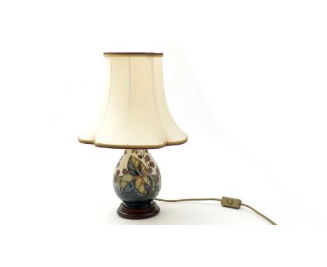 A Moorcroft blackberry pattern lamp of pear shape with wooden base and cream fabric shade, the ceramic 18cms.