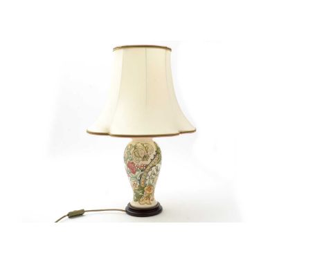 A Moorcroft lamp decorated with thistles and orchids on a cream ground, fitted wood base, cream fabric shade, the ceramic bas
