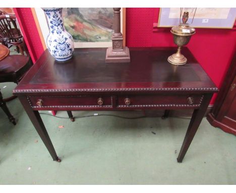 An Edwardian mahogany writing table with beaded edge decoration over two frieze drawers on square tapering legs and ceramic c