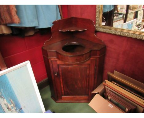 An early Victorian flame mahogany corner washstand, the raised back over a ceramic wash bowl insert and single door cupboard,