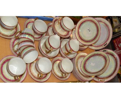 A Continental porcelain tea service,  for eight, in a lustre ground, banded in ruby picked out in gilt, c.1910