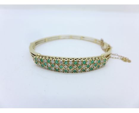 A 9ct gold, diamond and emerald bangle, 15.3g