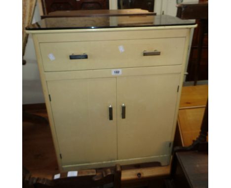 A 24" 1930`s "Ifco" painted wood bathroom cabinet with black glass top, long drawer and pair of cupboard doors under, set on 