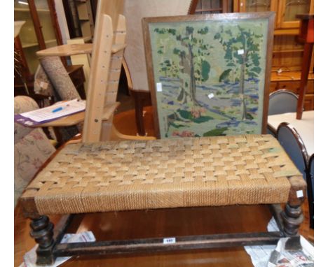 An antique stained oak duet footstool with woven string top and turned supports - sold with a woolwork panel firescreen