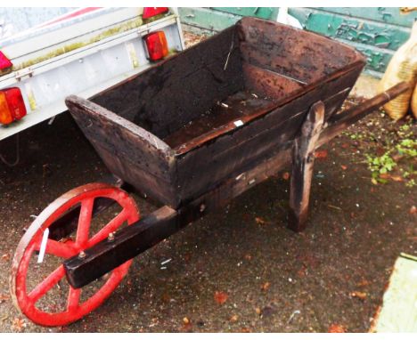 A vintage wooden wheelbarrow with large cast iron wheel