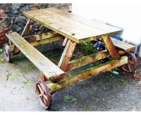 An large garden bench table on cast iron wheels