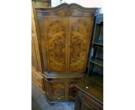 A 34" reproduction figured walnut corner cupboard with two pairs of doors, slide and canted sides, set on bracket feet