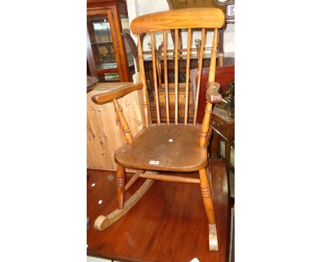 An antique high stick back rocking chair with solid elm seat and ring turned supports