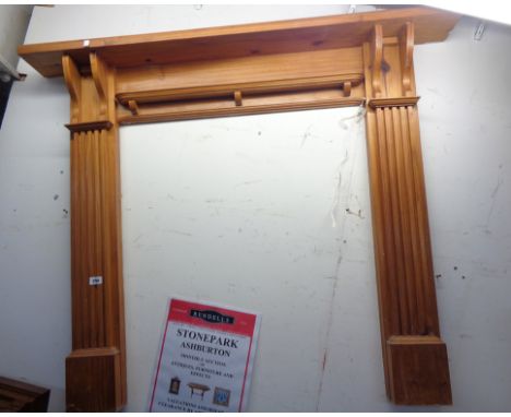 A modern polished pine fire surround with bracketed shelves and flanking fluted decoration