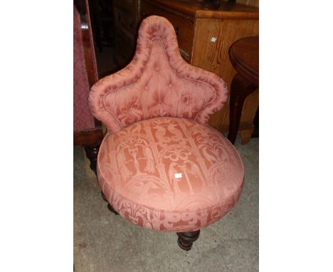 A Victorian upholstered boudoir shaped button back nursing chair with circular seat, set on turned legs and porcelain casters