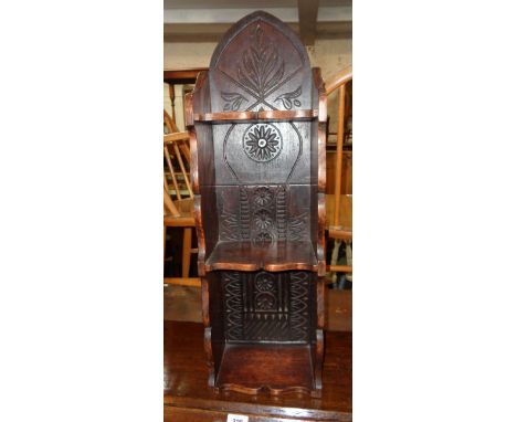 A small polished and carved oak wall mounted three shelf unit with mitre top and shaped sides