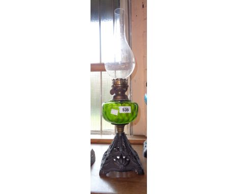 A Victorian table oil lamp with green glass reservoir and cast iron base