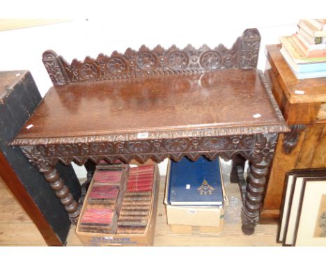 A 3' 5" Victorian carved oak side table with decorative raised back and apron, set on bobbin turned front supports