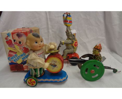 A vintage tin plate toy elephant on a tricycle, a man with a cannon and a later similar