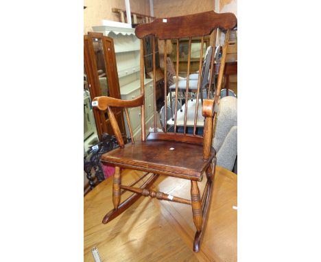 A 20th Century stained mixed wood high stick back rocking chair with laminated seat panel and turned supports