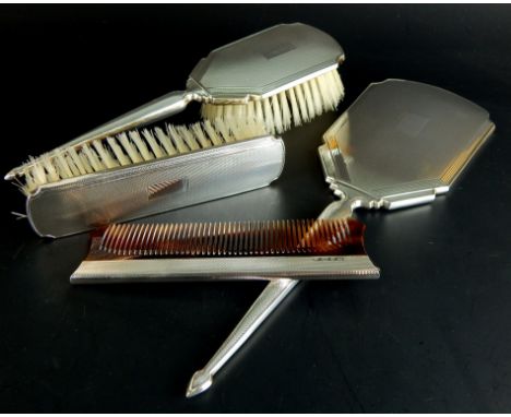 An associated engine turned silver four piece dressing table set, comprising hand mirror, two brushes and a comb