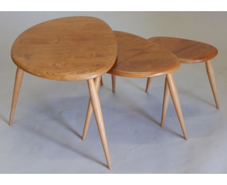 A nest of three Ercol light elm pebble shaped tables, each on turned legs, the largest 65cm wide.