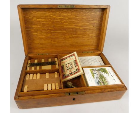 An oak box containing a number of playing card related items, to include four whist markers, etc.