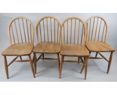 A set of four Ercol light stained ash and elm kitchen chairs, each with a spindle back.