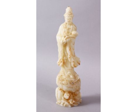 A CHINESE CARVED WHITE JADE FIGURE OF GUANYIN, stood uon a rocky outcrop holding a ruyi sceptre, 21cm high