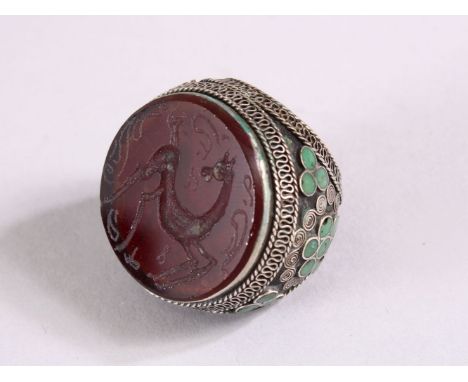 AN INDIAN SILVER INLAID INTAGLIO STYLE RING, the top carved with a horse, the sides with inlaid green hard stone possibly jad