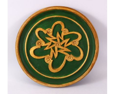 A TURKISH ISLAMIC CARVED WOODEN CIRCULAR WRITING PANEL, with a green base and raised gilded floral decoration, 39cm
