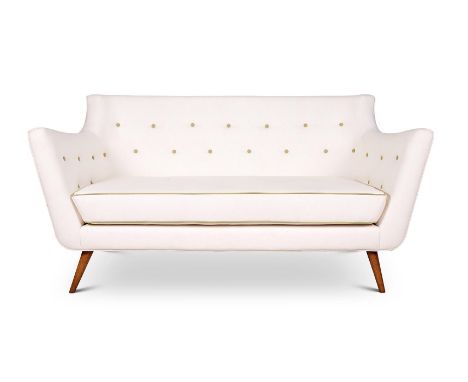 A CREAM LEATHERETTE UPHOLSTERED SOFA  MODERN, IN THE STYLE OF FINN JUHL With green buttons and piping, on beech legs 85cm hig