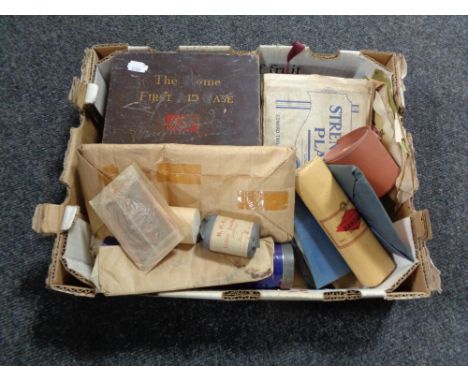 A box containing a vintage first aid kit and dressings. 