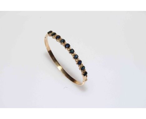 Sapphire and diamond 14k gold bangle, set with ten sapphires divided by pairs of brilliants.