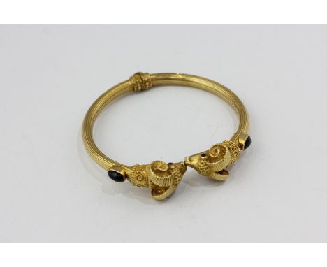 Ilias Lalaounis, an 18ct sprung bangle with cabochon rubies to the shoulders and rams' masks terminals
