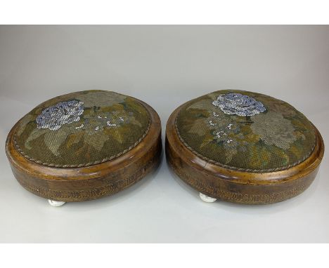 A pair of Victorian circular walnut footstools with narrow inlaid borders, needle and beadwork upholstered tops, raised on ce