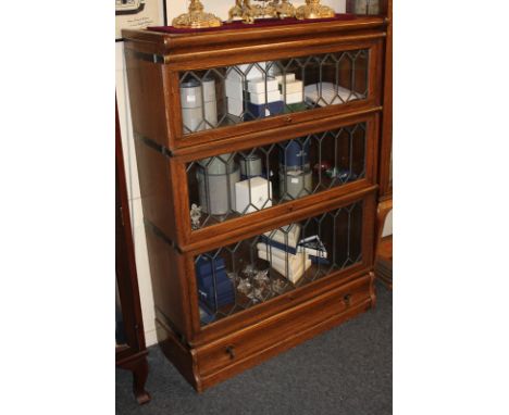 An oak Globe Wernicke three section bookcase with lead glass and single drawer, with maker's label, 86.5cm