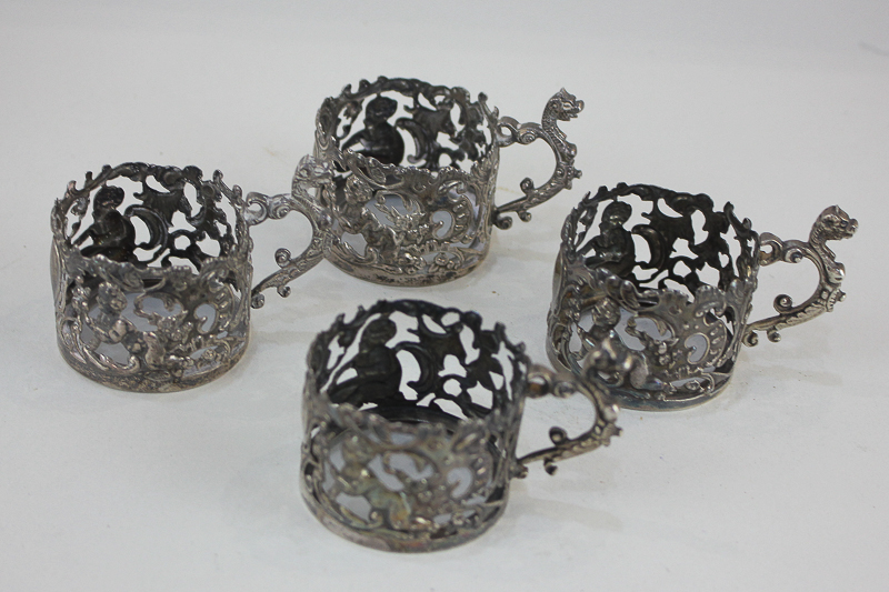 A set of four late Victorian silver cup holders decorated with cherubs