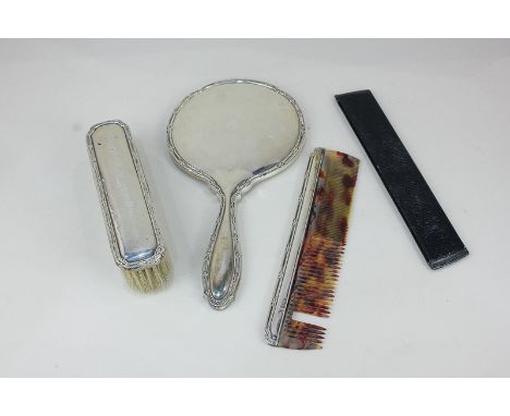 A George V silver mounted three-piece dressing table set of hand mirror, comb and clothes brush, maker William Neale, Birming