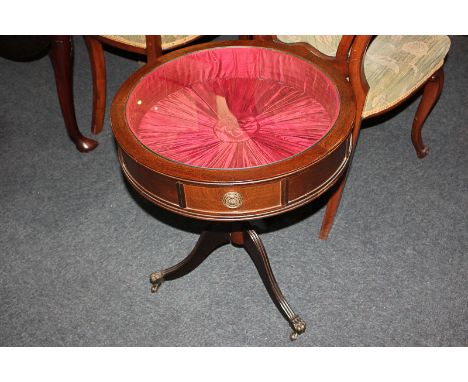 A circular mahogany display table with pull-out glass top enclosing fabric lined interior, on turned stem with outswept tripo