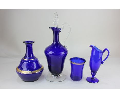 A blue glass wine flagon, a decanter with gilt banded decoration (lacks stopper), a beaker and a jug (LC)